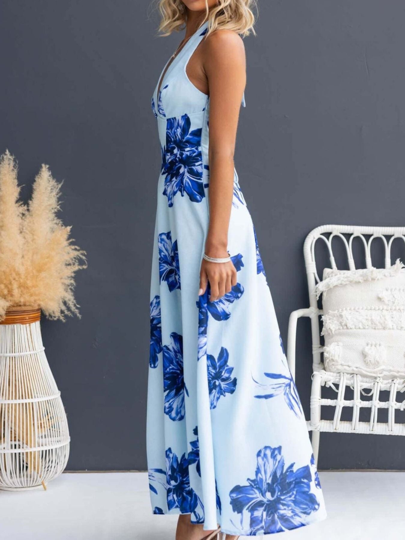 Woman wearing a blue floral dress in a room with decorative elements.