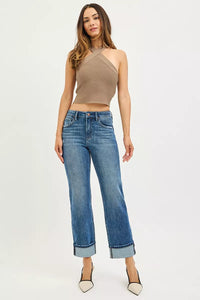 Woman wearing a beige halter top and blue jeans on a white background