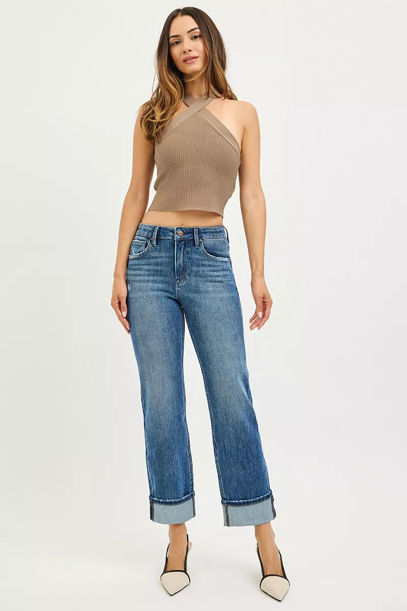 Woman wearing a beige halter top and blue jeans on a white background