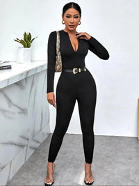 Woman wearing a black jumpsuit with a snake skin handbag in an indoor setting.