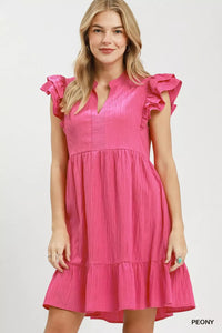 Woman wearing a pink dress with ruffled sleeves on a white background