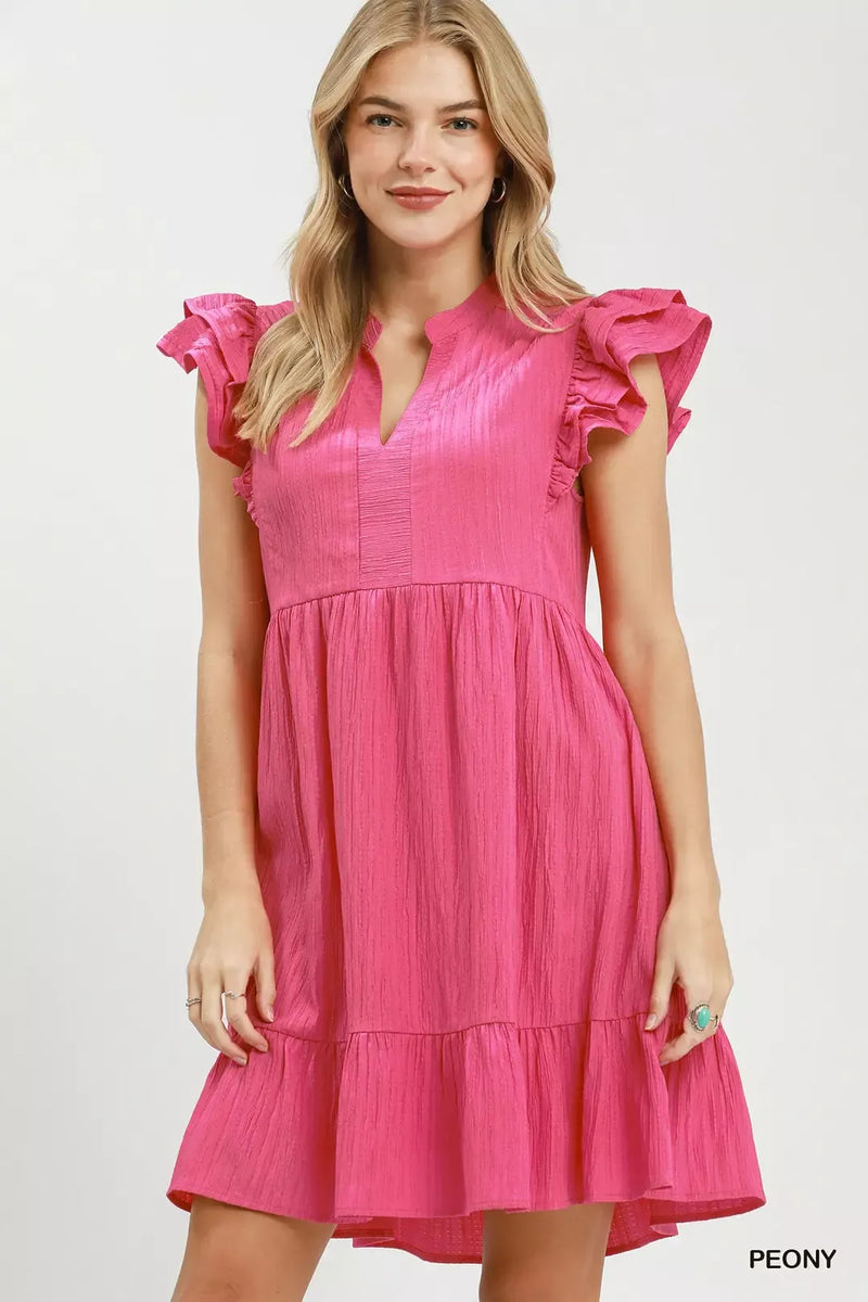 Woman wearing a pink dress with ruffled sleeves on a white background