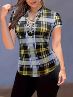 Woman wearing a plaid shirt with a lace-up front against a neutral background