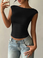 Person wearing a black top and light blue jeans against a neutral background