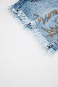 Denim shorts with fringe and embroidered design on a white background
