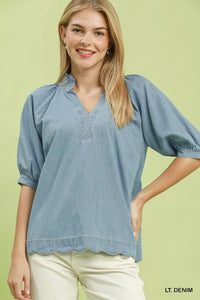 Woman wearing a light denim blouse against a light green background