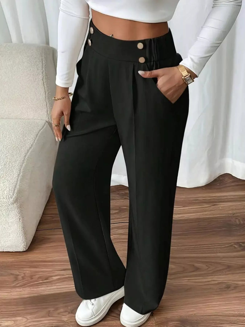 Person wearing black wide-leg pants with a white top and white sneakers on a wooden floor.