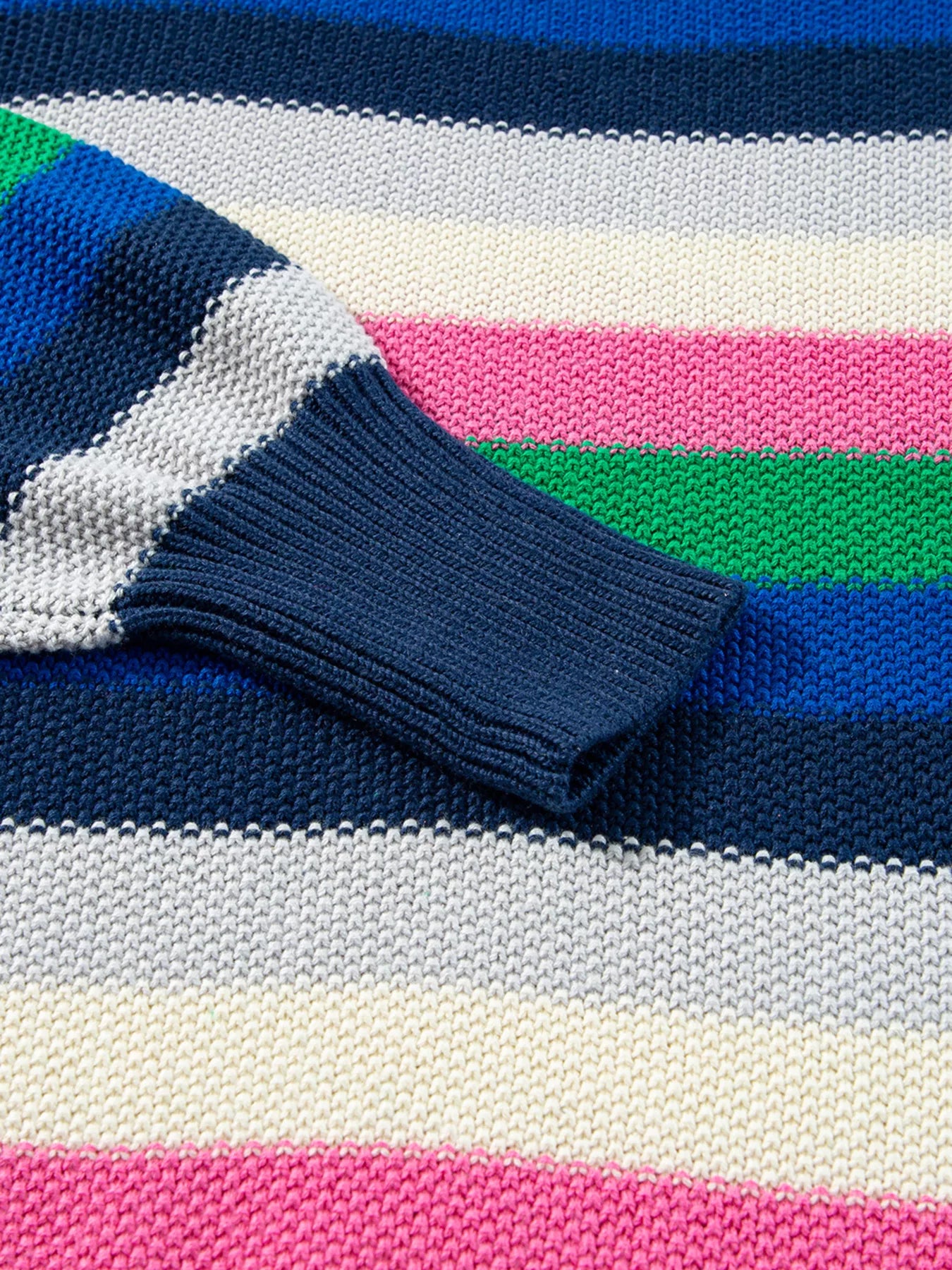 Close-up of a colorful striped sweater with blue, pink, green, and white stripes.