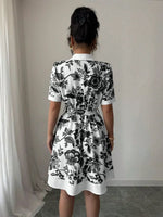 Person wearing a black and white floral dress against a plain background