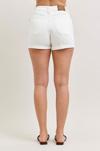White denim shorts worn by a person on a plain background