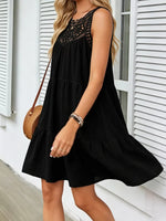 Woman wearing a black dress with lace details in front of a white building.
