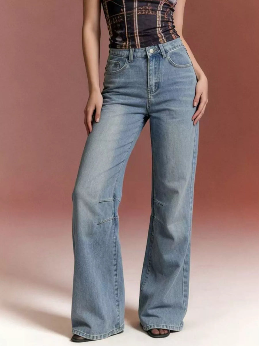 Person wearing blue flared jeans on a plain background