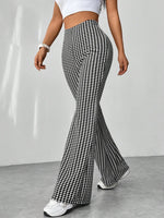 Person wearing houndstooth patterned flared pants on a plain background