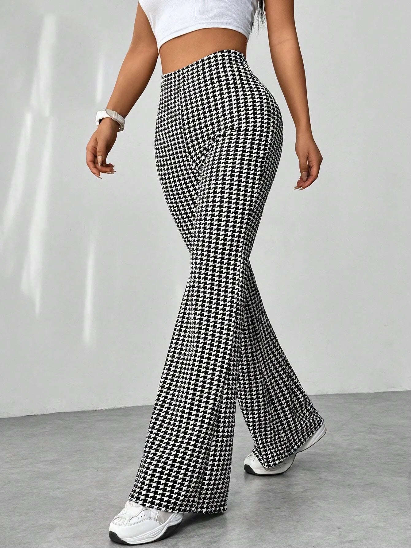 Person wearing houndstooth patterned flared pants on a plain background