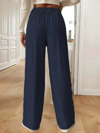 Navy blue wide-leg pants worn by a person indoors.