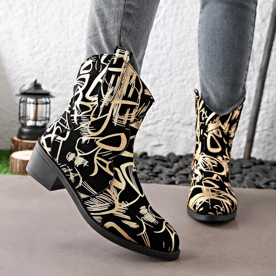 Black and gold patterned boots worn with gray pants on a neutral background