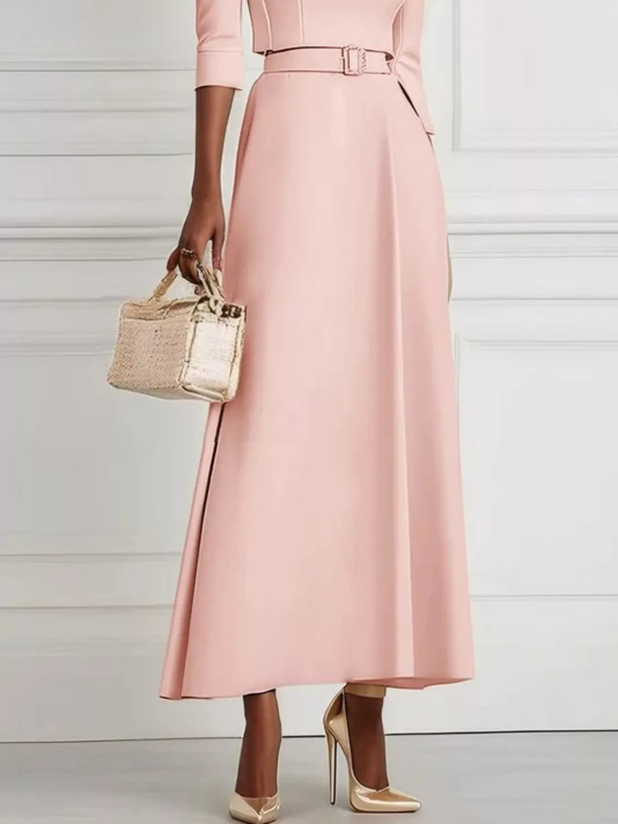 Person wearing a pink coat holding a gold handbag against a light background