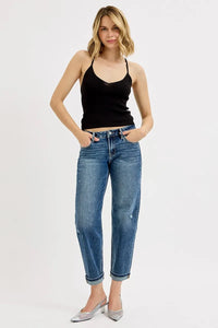 Woman wearing a black tank top and blue jeans on a white background