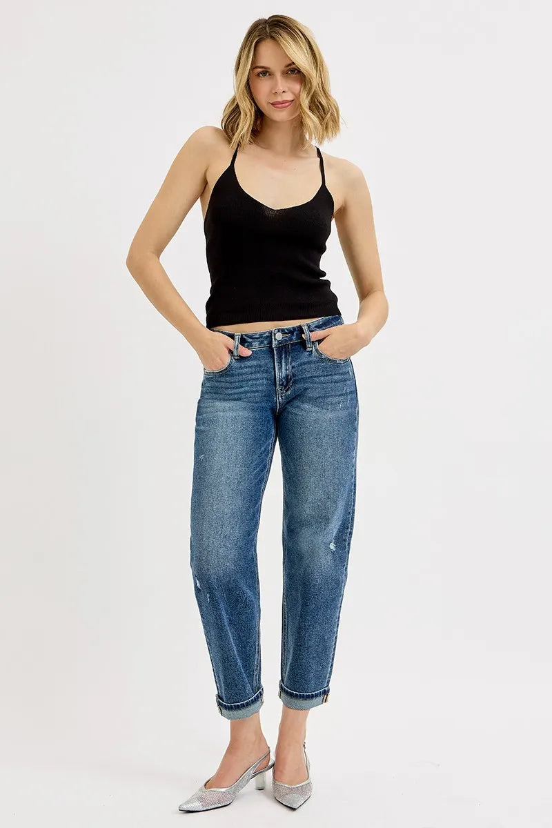 Woman wearing a black tank top and blue jeans on a white background