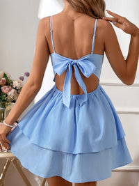Light blue dress with open back and bow detail worn by a person, with flowers in the background.