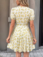 Woman wearing a floral dress with yellow flowers against a neutral background