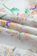 Floral patterned fabric with orange, purple, and green colors on a white background