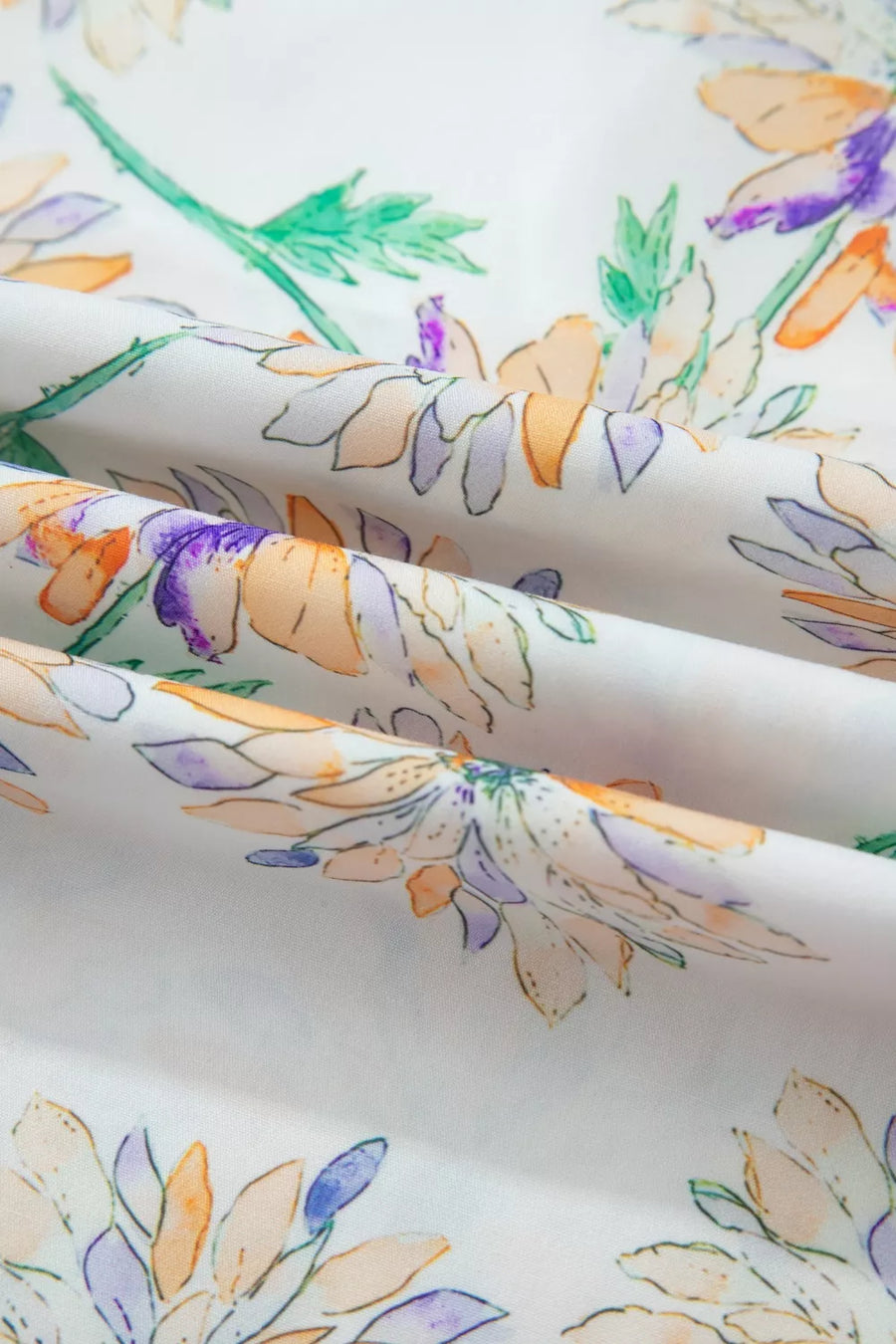 Floral patterned fabric with orange, purple, and green colors on a white background
