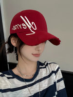 Person wearing a red cap with white text and a striped shirt.