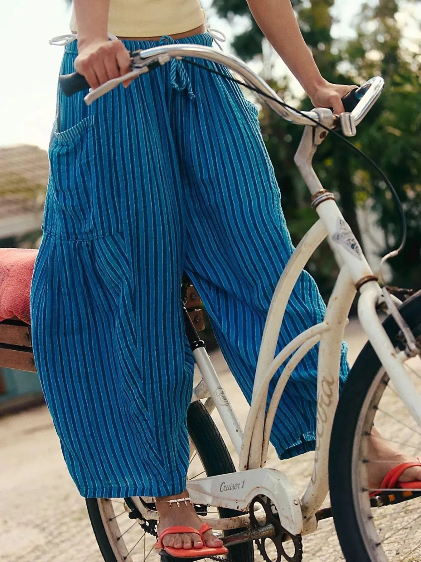 Person wearing blue pants standing next to a bicycle outdoors