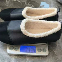 Pair of black shoes with white soles on a digital scale showing weight.
