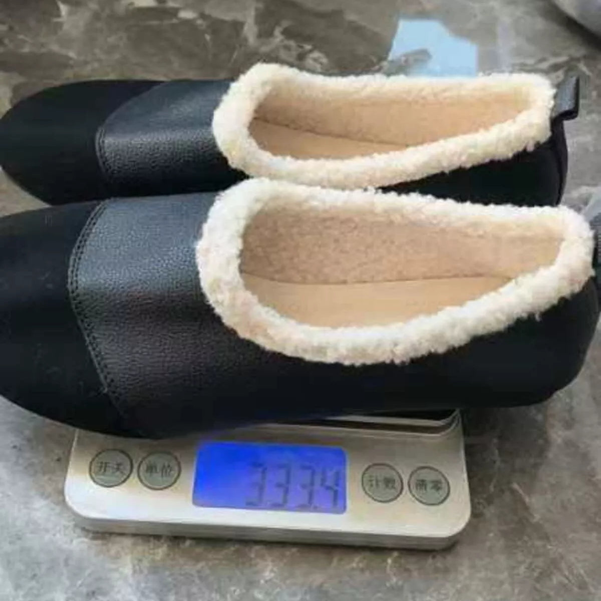 Pair of black shoes with white soles on a digital scale showing weight.