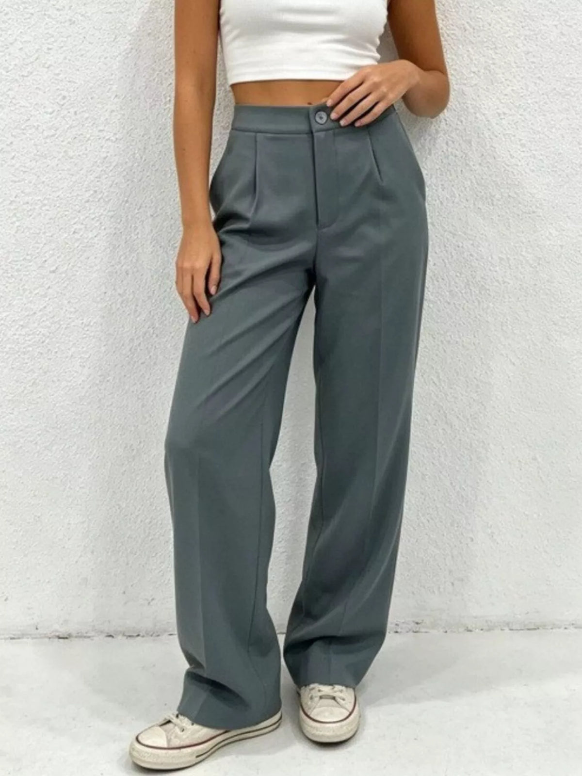 Person wearing gray wide-leg pants and a white top against a light background