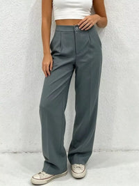 Person wearing gray wide-leg pants and a white top against a light background
