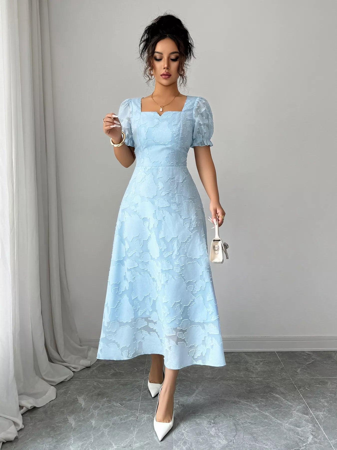 Woman wearing a light blue lace dress against a gray background