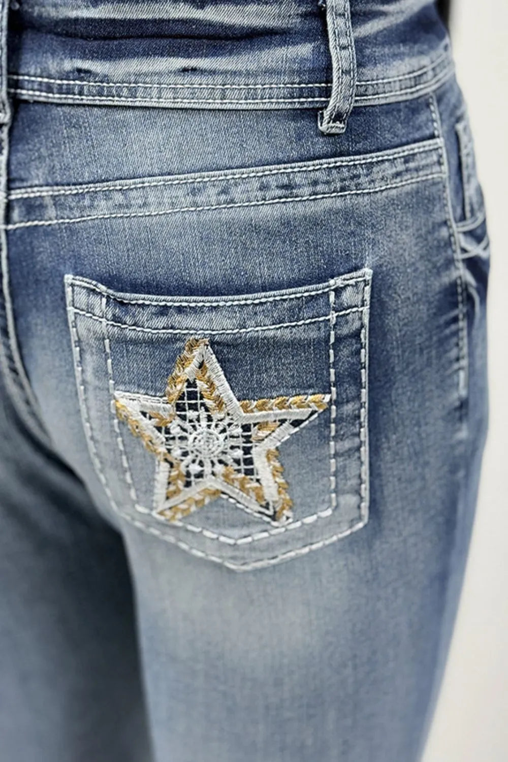 Close-up of blue jeans with a star patch on the pocket.