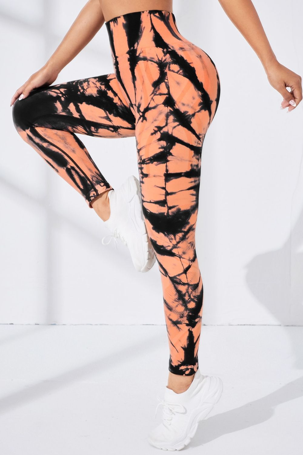 Person wearing tie-dye leggings with black and orange pattern on a white background