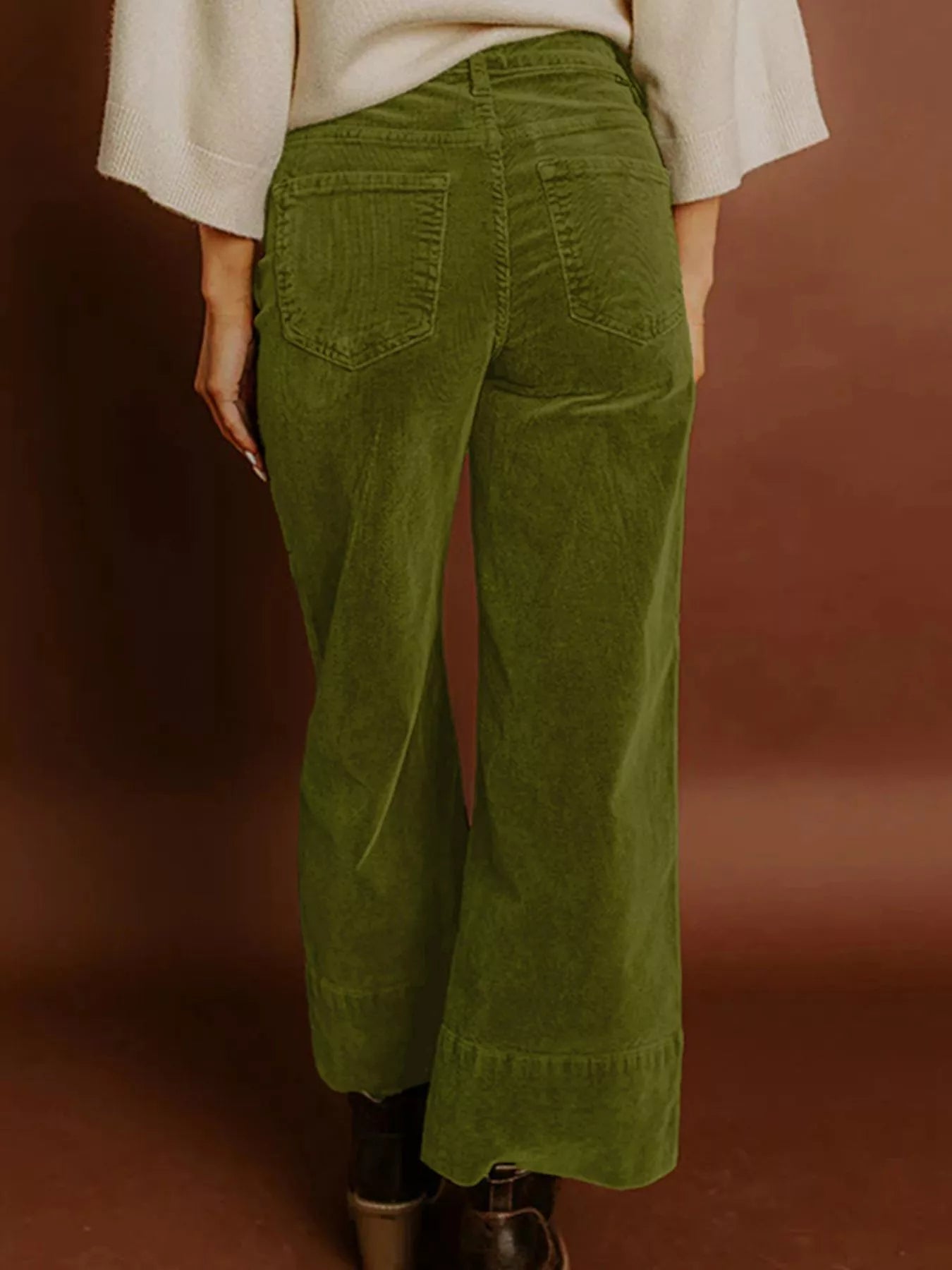 Green corduroy pants worn by a person on a brown background