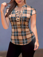 Woman wearing a plaid top with a brown and green pattern against a gray background