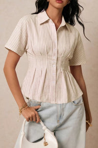 Woman wearing a beige striped shirt and light blue jeans against a neutral background