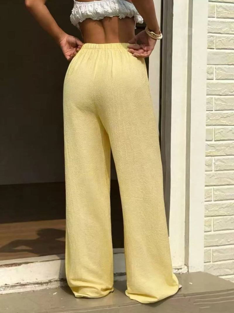 Person wearing yellow pants standing in front of a brick wall.