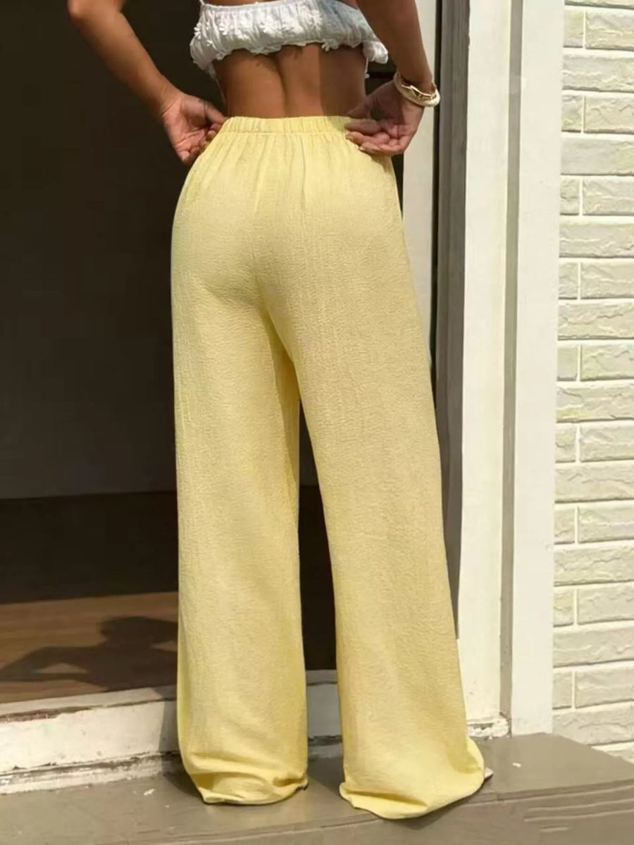 Person wearing yellow pants standing in front of a brick wall.