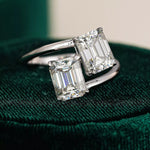 Diamond ring with emerald-cut stones on a green velvet cushion