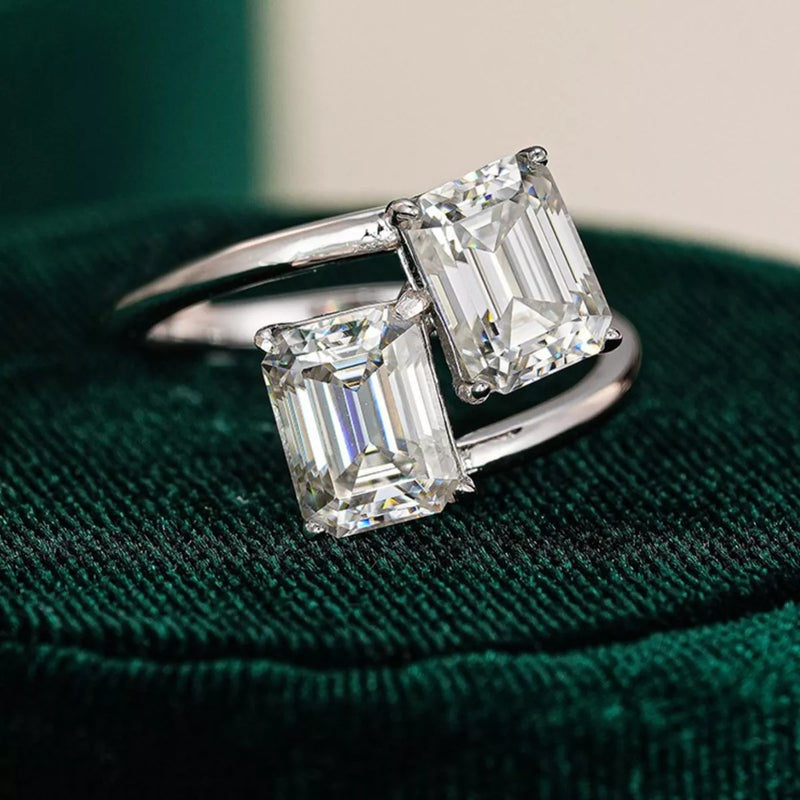 Diamond ring with emerald-cut stones on a green velvet cushion