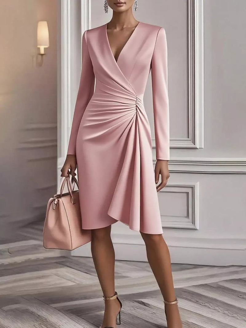 Woman wearing a pink dress with long sleeves in an elegant interior setting.