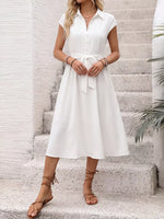 Woman wearing a white dress standing on stone steps with a neutral background