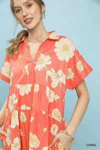 Woman wearing a coral dress with floral pattern against a light blue background