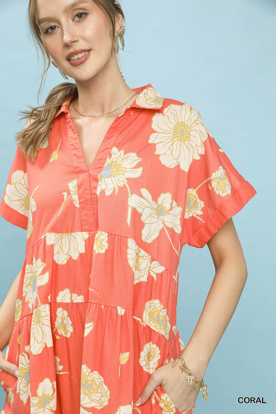 Woman wearing a coral dress with floral pattern against a light blue background