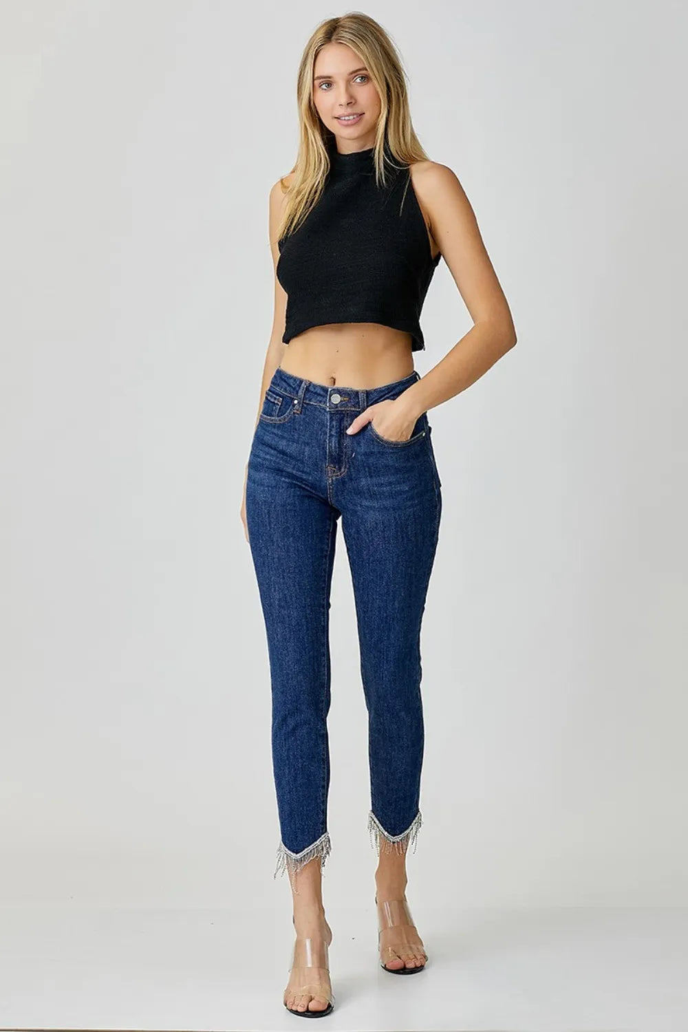 Woman wearing blue jeans and a black top on a white background