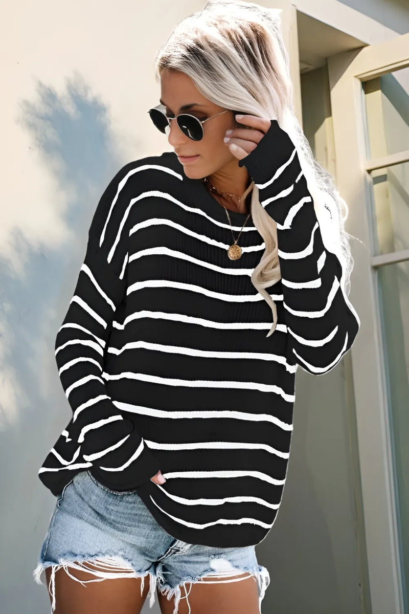 Woman wearing a black and white striped sweater and denim shorts outdoors.