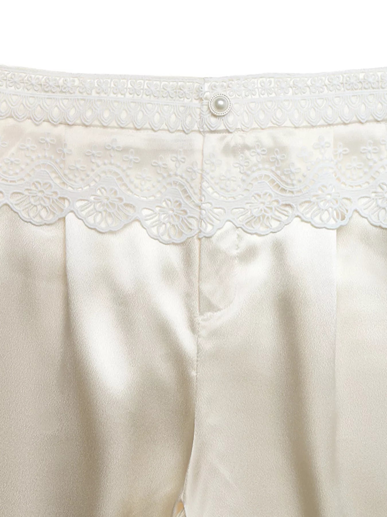 Close-up of a white garment with lace detailing on a white background